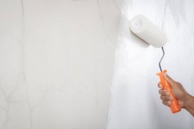 Ressam iç duvarı beyaza boyuyor.