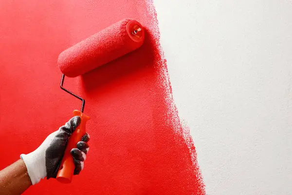 Roller Brush Painting, Worker painting on surface wall  Painting apartment, renovating with red color  paint. Leave empty copy space white to write descriptive text beside.