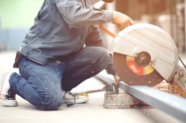 A worker cutting steel with a steel cutting machine sparked at a construction site.	