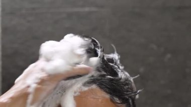 Bir adam saçını kepek önleyici ile yıkıyor.