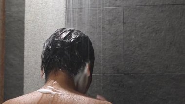 Bir adam saçını kepek önleyici ile yıkıyor.