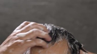 Bir adam saçını kepek önleyici ile yıkıyor.