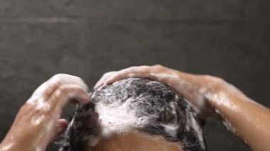 Bir adam saçını kepek önleyici ile yıkıyor.