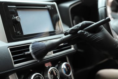 Personel araba tamirhanesinde araba kliması temizliyor.