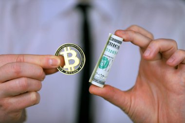 Bitcoin ve bir tomar doları elinde tutan bir iş adamı..