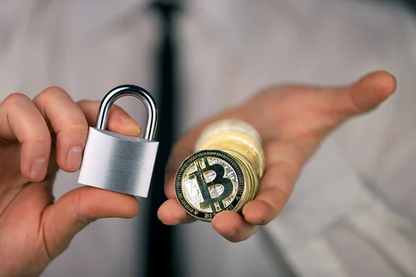 一位商人手里拿着一把银色挂锁和实物版的比特币 禁止加密货币 限制或安全 — 图库照片#
