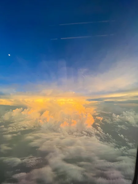 looking out airplane window into sunset in the clouds