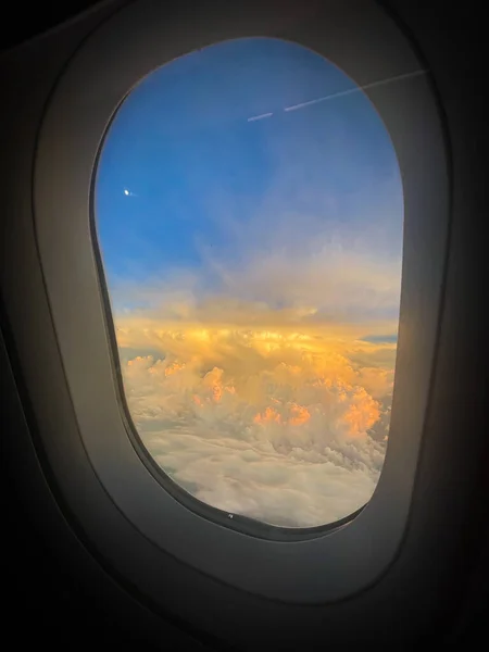 looking out airplane window into sunset in the clouds
