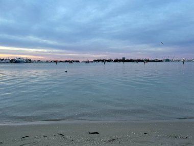 Gri gökyüzü ve bulutlar şafak vakti kıyı sularında