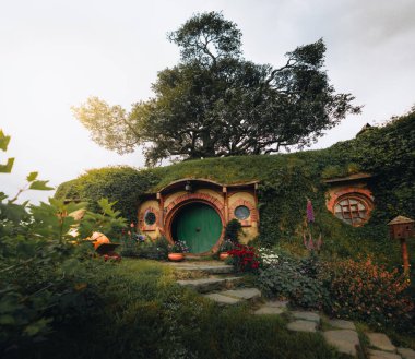 Bilbo Baggins 'in evi ve Hobbiton film setindeki hobbit bahçesi, Yeni Zelanda. Yazın çekilmiş. Güneş ışığı yansıması. Seyahat ve macera konsepti. Fotoğraf Yeni Zelanda 'da çekildi.