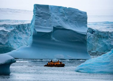Turistlerle dolu tekne, Antarktika yarımadası, Ilulissat sera arazisi yakınlarındaki körfezde sürüklenen dev buzdağlarını keşfediyor. Fotoğraf.