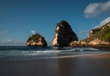 Muhteşem Elmas Sahili manzarası güzel bir gündoğumu sırasında turkuaz bir deniz tarafından yıkandı. Diamond Beach, Nusa Penida 'nın doğu ucunda el değmemiş, beyaz kumlu ve ipeksi mavi bir su koyudur.