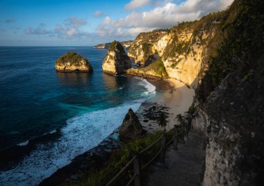 Muhteşem Elmas Sahili manzarası güzel bir gündoğumu sırasında turkuaz bir deniz tarafından yıkandı. Diamond Beach, Nusa Penida 'nın doğu ucunda el değmemiş, beyaz kumlu ve ipeksi mavi bir su koyudur.