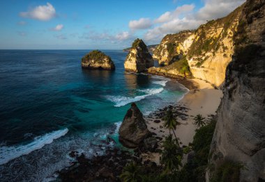 Muhteşem Elmas Sahili manzarası güzel bir gündoğumu sırasında turkuaz bir deniz tarafından yıkandı. Diamond Beach, Nusa Penida 'nın doğu ucunda el değmemiş, beyaz kumlu ve ipeksi mavi bir su koyudur.