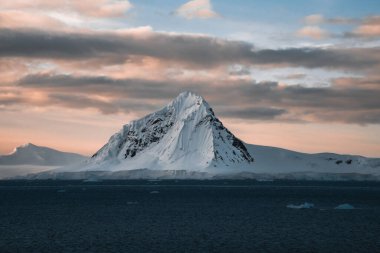 Antarktika 'da yüzen buzdağları olan güzel karlı dağlar. Küresel ısınma ve iklim değişikliği için seyahat kavramı. Kuzey Grönland. Gün batımı gökyüzü