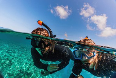 İki adamın, Avustralya tropikal adasında, Queensland 'da Büyük Set resifinde turkuaz okyanus suyunda şnorkelle yüzerken çekilmiş fotoğrafı.