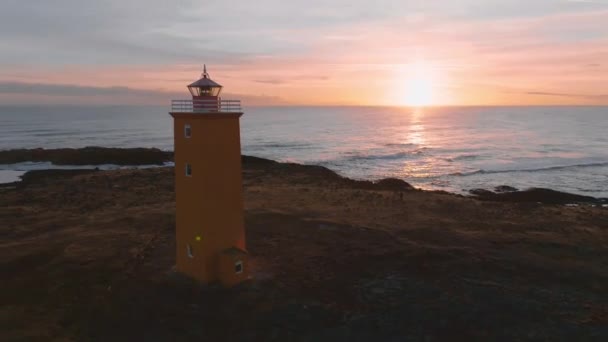アイスランド沿岸のオレンジ灯台の空中ドーン映像 カラフルな灯台の夏時間 南アイスランド 崖の上の嵐 晴れた日 空中ドローンビュー — ストック動画