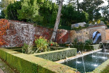 Granada, İspanya - 29 Kasım 2021: The Generalife avlusunun manzarası, ünlü çeşmesi ve bahçesiyle bir kemer boyunca. Granada, İspanya, Avrupa 'daki Alhambra de Granada kompleksi aydınlık bir kış günü.