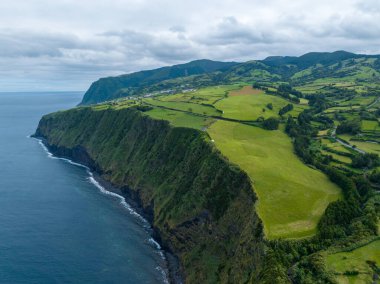 Azores 'deki Sao Miguel adasının kuzeydoğu kıyısında inanılmaz bir manzara. Uçurumun panoramik manzarası, denize giden bir yol ve küçük bir balıkçı limanı. Portekiz 'in turistik cazibesi.