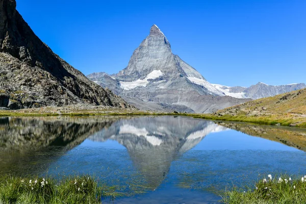 stock image Serene summer landscape, the famous Matterhorn mountain in Zermatt, Switzerland, gently mirrors its grandeur in the calm waters of Riffelsee. Breathtaking alpine view. Beautiful landscape.