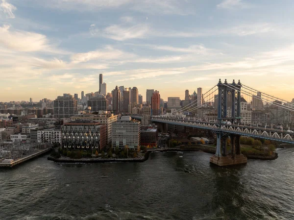 Aerial view of the Manhattan Bridge spanning the East River with the New York City skyline in the backdrop on a clear day.