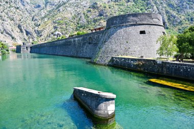 Kampana kulesi ve dağları olan ortaçağ kale duvarları ve Scurda nehri önünde yeşil sular, Kotor Körfezi, Karadağ