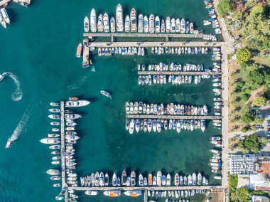 Karadağ 'ın Budva kentindeki tekne rıhtımı ve yat limanının havadan aşağı görüntüsü. Beyaz özel motorlu tekneler Adriyatik deniz kıyısındaki iskeleye demirlemiş. Yat kulübü tekneleri park ediyor..
