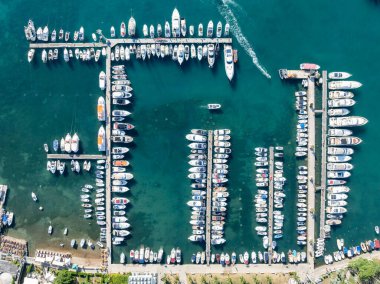 Karadağ 'ın Budva kentindeki tekne rıhtımı ve yat limanının havadan aşağı görüntüsü. Beyaz özel motorlu tekneler Adriyatik deniz kıyısındaki iskeleye demirlemiş. Yat kulübü tekneleri park ediyor..