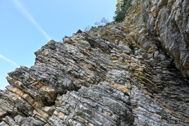 Karadağ 'ın Budva kentindeki bir kayanın üzerindeki katmanlı mineral oluşumlarının dokusu. Geometrik soyut çapraz çizgiler doğada. Açık bej-sarı desen
