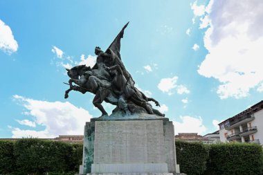 7 Ağustos 2023 - İtalya 'nın Puglia şehrinde Gravina savaş anıtı olan belediye villası. Çiçek tarlaları ve parktaki iyi korunmuş bahçenin çimenleri. Kadim saati olan kule..