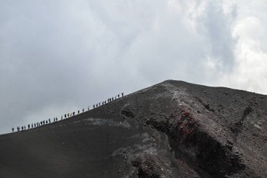 Sicilya 'nın Etna Dağı boyunca yürüyen yürüyüşçüler - İtalya' nın en uzun aktif yanardağı. Etna volkanının geniş panoramik görüntüsü, yokuştaki sönmüş kraterler, volkanik aktivite izleri..