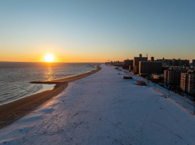 Brooklyn, New York 'ta kış günbatımında Coney Island Sahili' ni kaplayan kar manzarası