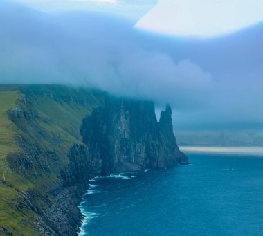 Faroe Islands Trollkonufingur rock, also called The Witchs Finger on the island of Vagar. Trollkonufingur is a freestanding sea stack rock on the east of Sandavagur village on the Faroe Islands. clipart