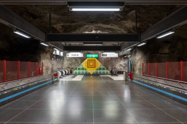 İsveç, Stockholm, 4 Ağustos 2024: Yeraltı metro tüneli istasyonu Vastra Skogen (mavi hat, merkez istasyon) renkli desenli mağaralar duvarlar ve tavan.