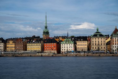 Serene Stockholm günbatımında gökyüzü, tarihi mimari, sakin rıhtım ve Skeppsholmen 'den seyredilen tekneler. Sakin İskandinav cazibesi.