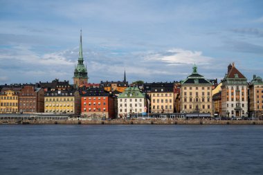 Serene Stockholm günbatımında gökyüzü, tarihi mimari, sakin rıhtım ve Skeppsholmen 'den seyredilen tekneler. Sakin İskandinav cazibesi.
