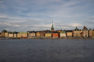 Serene Stockholm günbatımında gökyüzü, tarihi mimari, sakin rıhtım ve Skeppsholmen 'den seyredilen tekneler. Sakin İskandinav cazibesi.