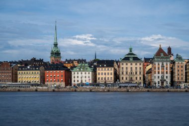 Serene Stockholm günbatımında gökyüzü, tarihi mimari, sakin rıhtım ve Skeppsholmen 'den seyredilen tekneler. Sakin İskandinav cazibesi.