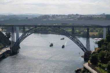 Dona Maria Pia Köprüsü ve Douro Nehri boyunca uzanan Sao Joao Köprüsü, sakin sularda manzaralı yamaçlar ve botlarla