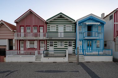 Costa Nova, Portekiz - 16 Ağustos 2024: Palheiros adı verilen kırmızı, mavi ve yeşil çizgili renkli çizgili evler. Costa Nova do Prado, Atlantik kıyısında Aveiro yakınlarında bir sahil köyü..