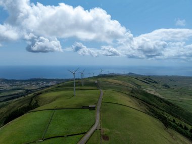 Miradouro da Serra do Cume 'dan yel değirmenleri, Azores' deki Terceira Adası 'ndaki geniş düz alana çiftçi tarlalarından oluşan yamalı örtüsüyle bakıyor.