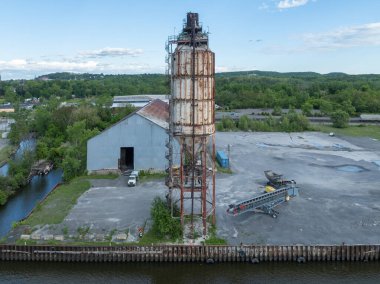 Hudson, New York 'ta terk edilmiş, paslı, spiral merdivenli silo. Aşırı gelişmiş bitki örtüsü ve çürüyen endüstriyel yapı unutulmuş bir geçmişe işaret ediyor..