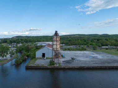 Hudson, New York 'ta terk edilmiş, paslı, spiral merdivenli silo. Aşırı gelişmiş bitki örtüsü ve çürüyen endüstriyel yapı unutulmuş bir geçmişe işaret ediyor..