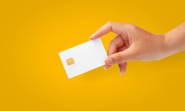 İş ve finans için sarı arka planda boş bir kredi kartı tutan kadın el.
