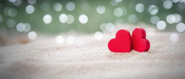 Kumlu plajda iki tahta kırmızı kalp. Light Bokeh 'li. Aşk ve Çift kavramı. Sevgililer Günü Konsepti
