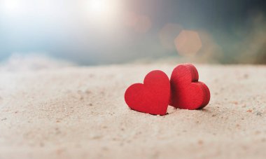 Güneşli kumlu kumlu bir plajda iki tahta kırmızı kalp, Aşk ve Çift kavramı. Sevgililer Günü Konsepti