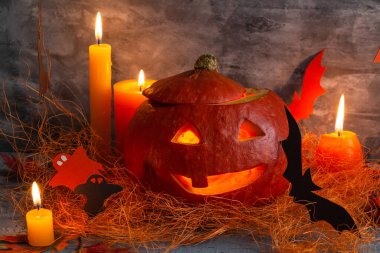 Cadılar Bayramı konsepti, balkabağı ve gri arka plandaki mumların bileşimi, balkabağından gelen balkabağı feneri, atmosferik cadılar bayramı arkaplanı, gülen nazik balkabağı. Yüksek kalite fotoğraf