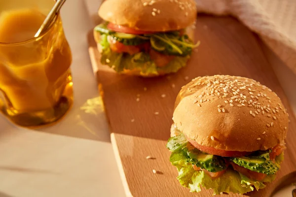 アメリカの古典的なハンバーガーの健康的な代替 ハードシャドウの下でスモークサーモン キュウリ トマトとレタスと魚バーガー — ストック写真