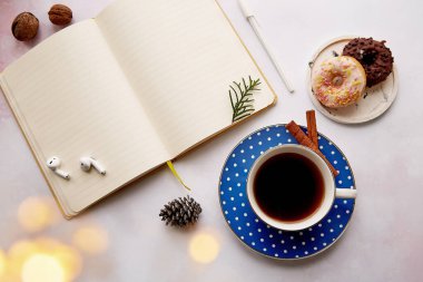 Kahve fincanı, donut, kulaklık, ev ofisinde Noel süslemeleri olan boş bir not defteri. Yeni yıl çözümü, yeni başlangıç ve hedef listesi kavramı.