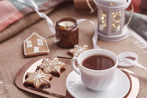 Atmospheric Christmas mood with homemade gingerbread cookies, cup of cocoa, flashlight, candles cozy background.